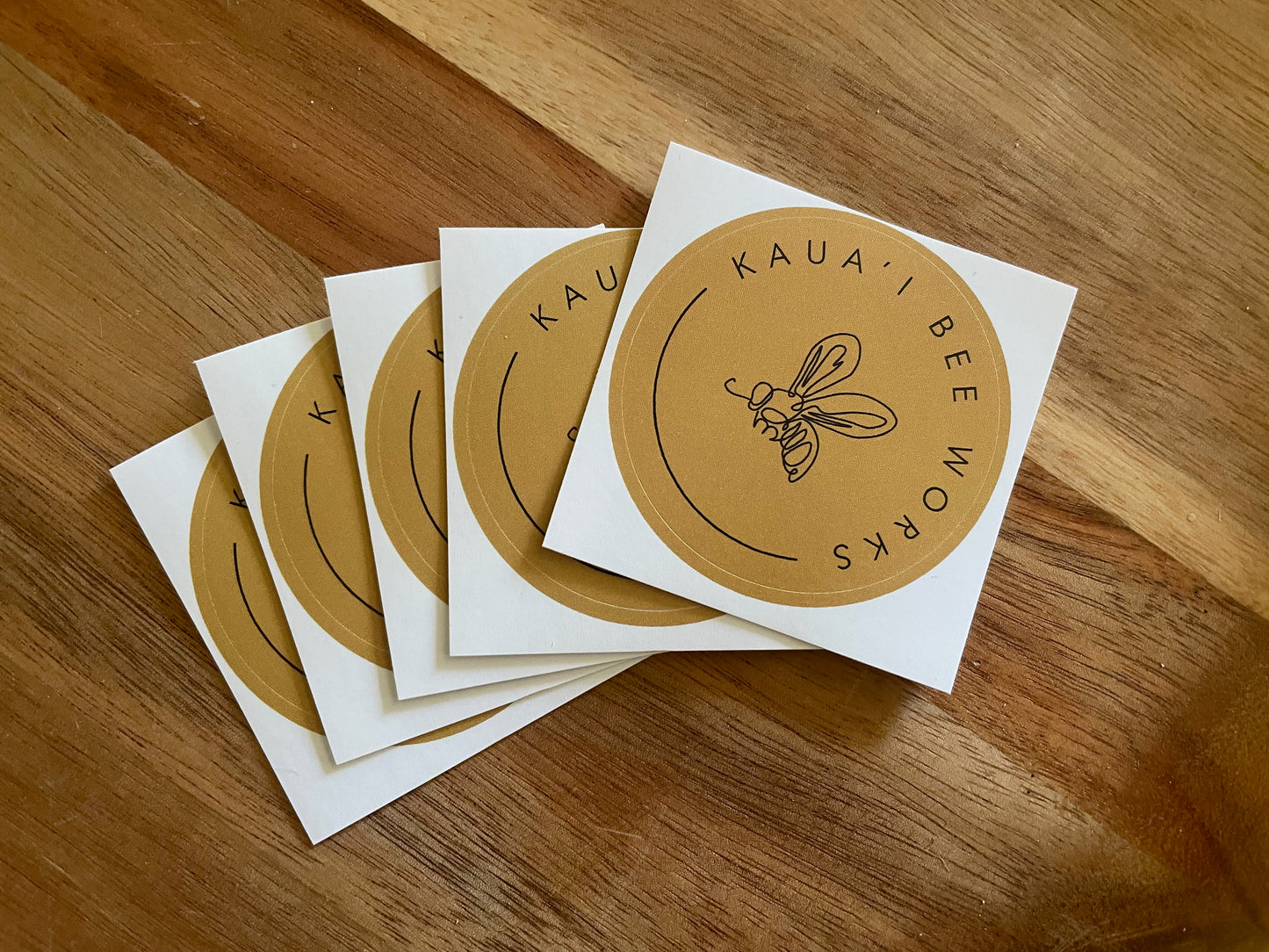 Kaua'i Bee Works 2" round sticker on wooden surface